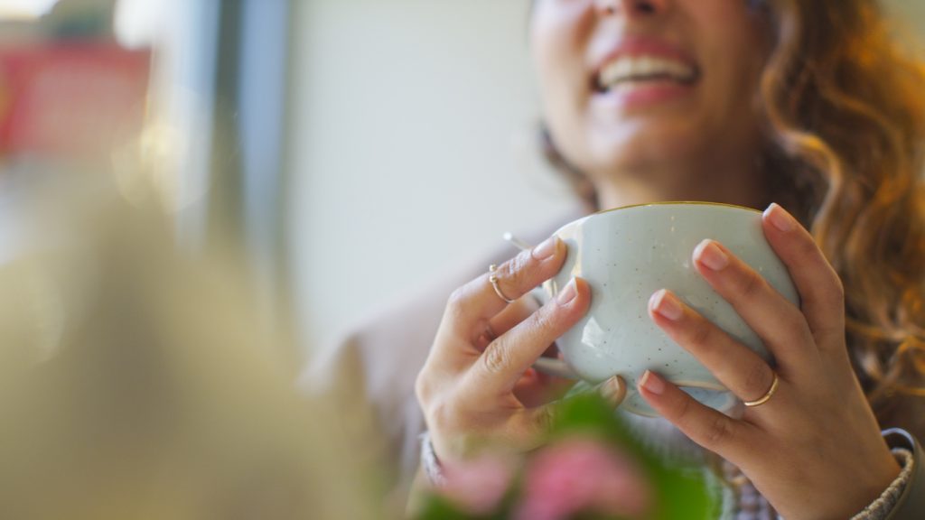 image of a woman holding a cup whilst talking