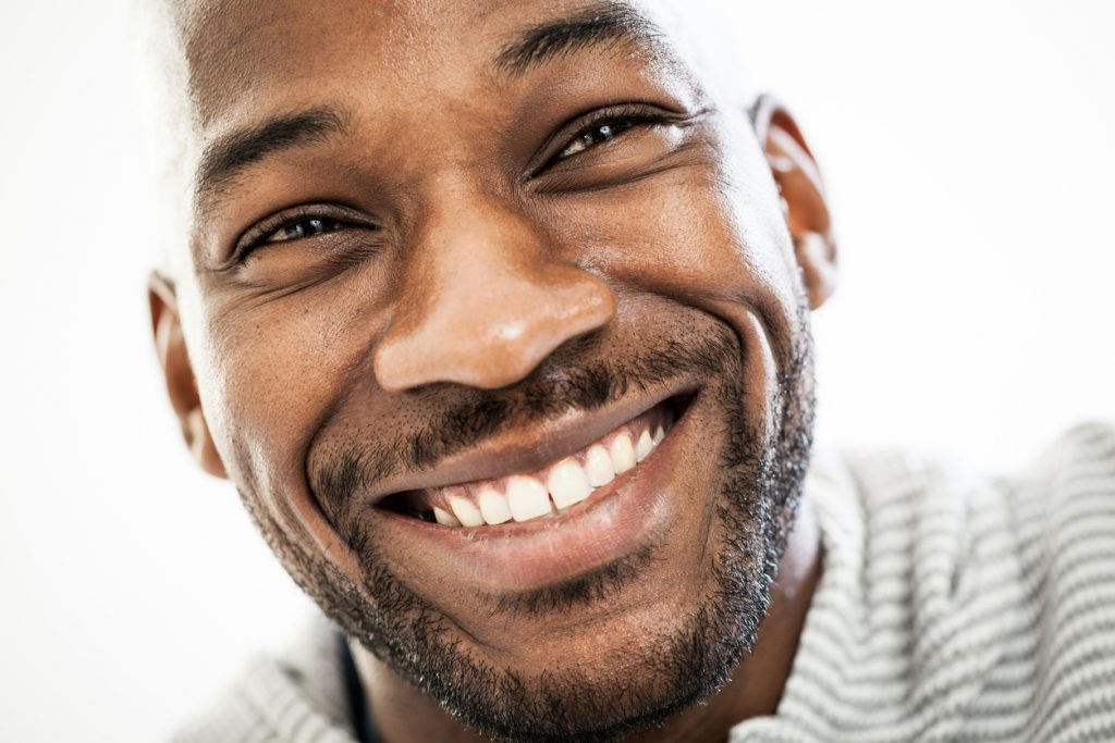 a close up view of a man with a smiling face and bright white teeth