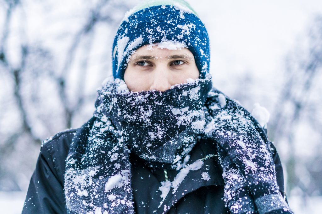 close up of a man's face with scarf covered by snow on a winter day