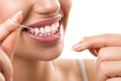 A woman cleaning her teeth with dental floss