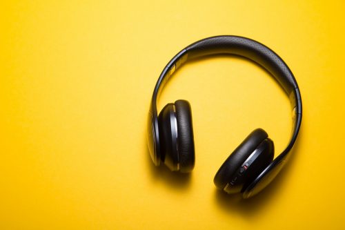 a pair of black wireless headphones on a yellow background